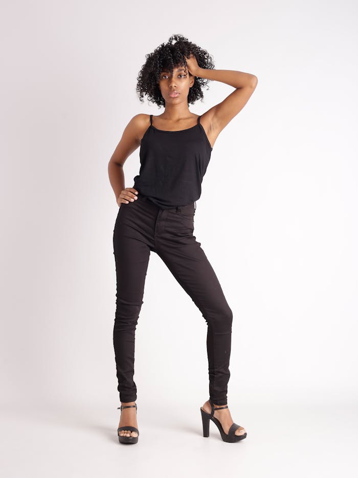 Confident woman posing in black outfit with stylish afro hair, showcasing fashion and elegance.